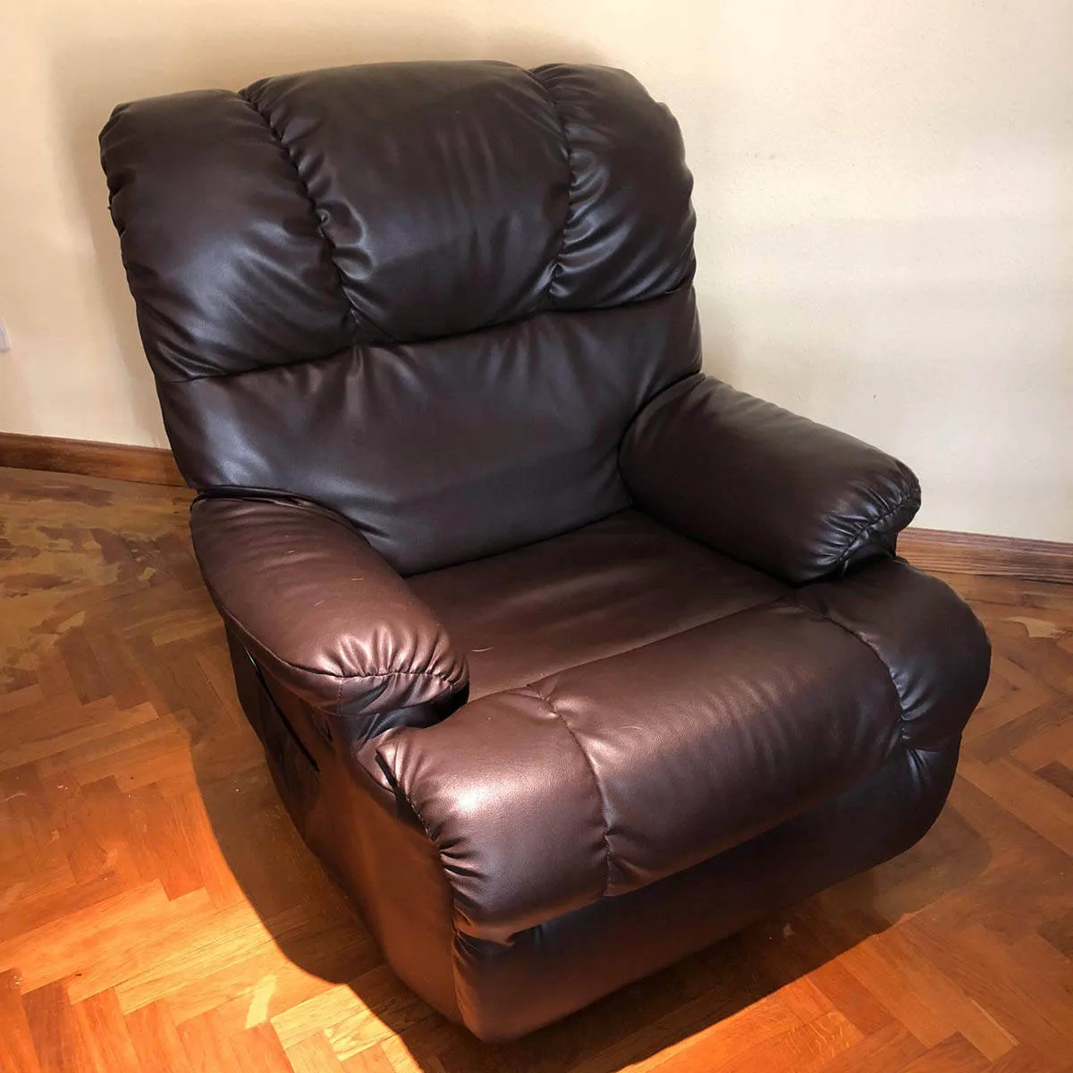 Sillón de piel marrón sobre suelo de parqué, antes de la mudanza